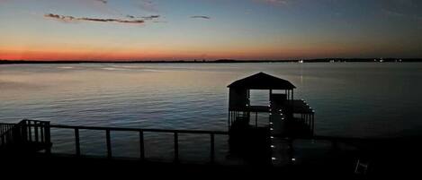 Un muelle con un pequeño refugio al final, con vista a aguas tranquilas durante el atardecer.