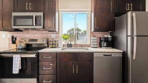 A modern kitchen with dark wood cabinets, stainless steel appliances, a granite countertop, and a window with a view of the outdoors.