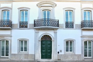 A building with a green door, multiple windows, and balconies with wrought iron railings.