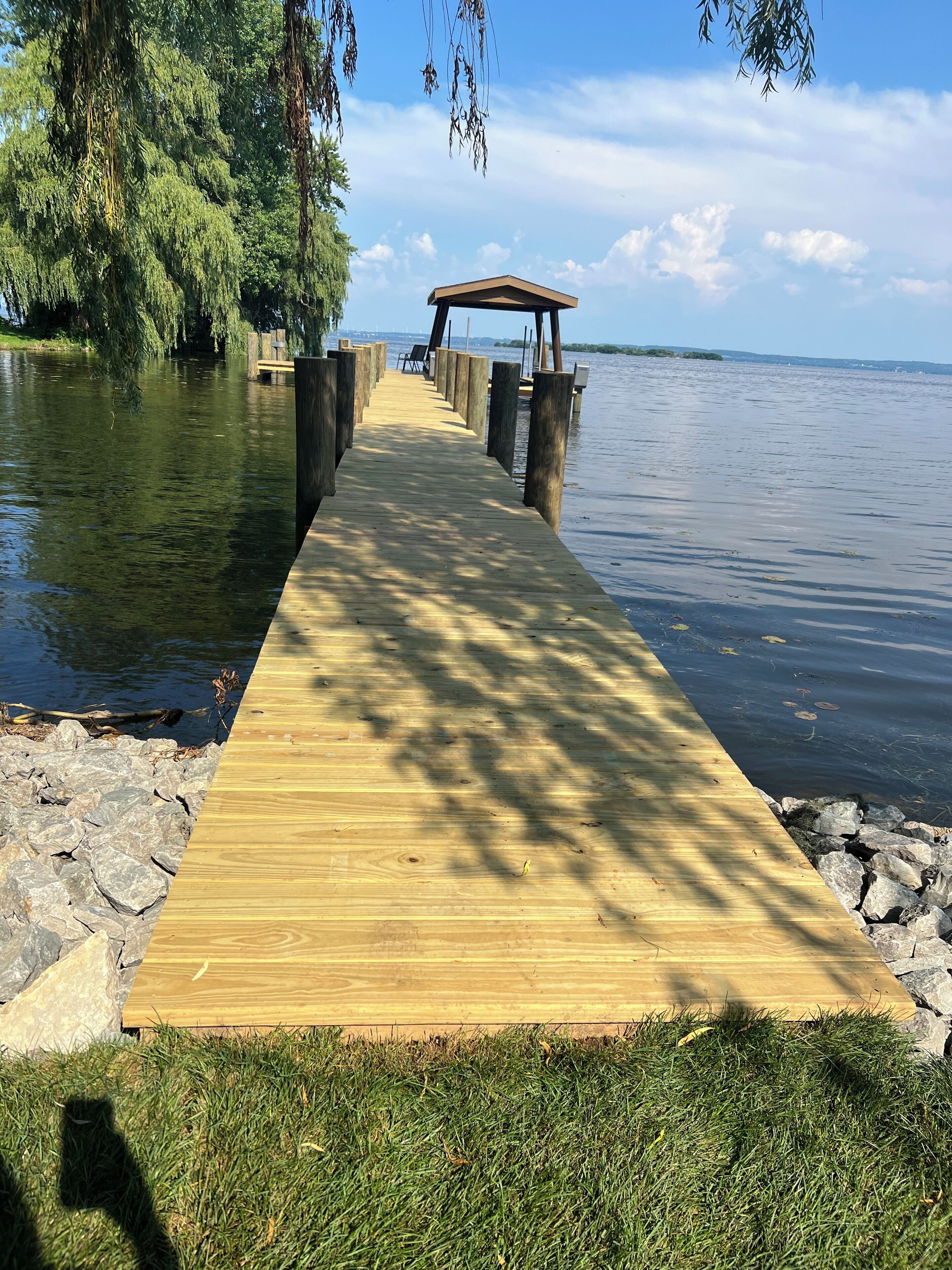 A wooden pier extending into calm water, with a gazebo at the end.