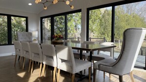 Un comedor moderno con una mesa grande, seis sillas y una araña.