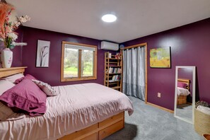 Un dormitorio con cama, estantería, ventana y espejo.