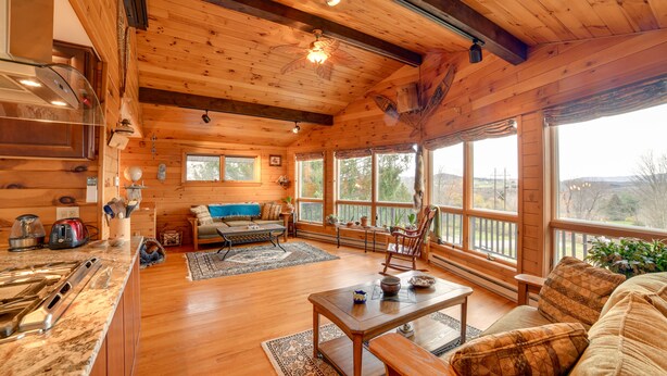 A spacious cabin with a wooden interior, a dining area, and large windows offering views of the outdoors.