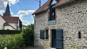 A stone building with a red-tiled roof, a small window, and a door. - Gite Climatisé les Lauriers (Essey)