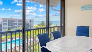 Ein Balkon mit Blick auf einen Swimmingpool und Gebäude, ein runder Tisch mit Stühlen und ein Schild an der Wand.