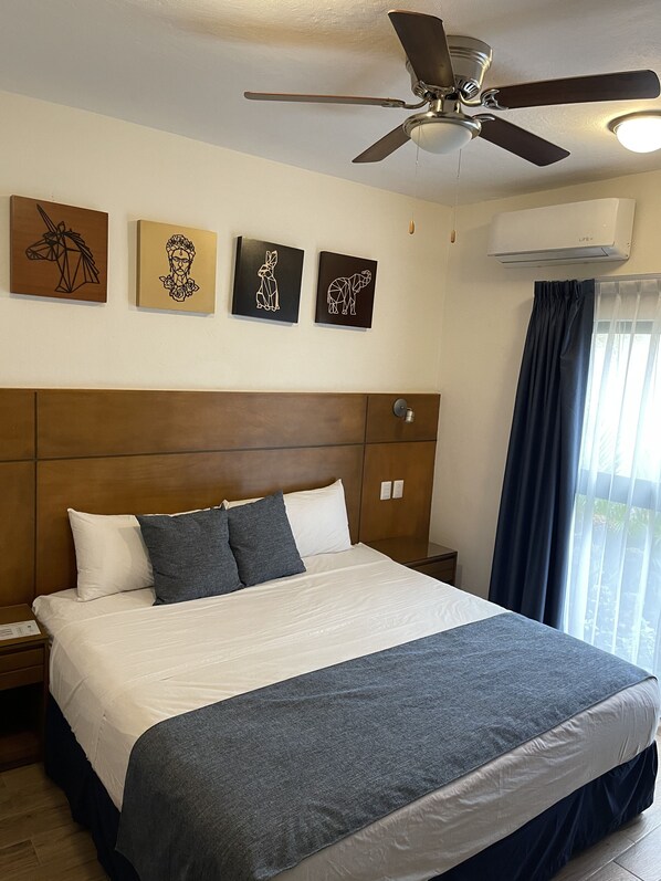 A hotel room with a large bed, a ceiling fan, an air conditioning unit, and artwork on the wall. - Hotel Reforma (Iguala de la Independencia)