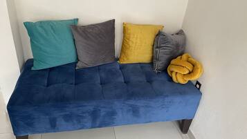 Un sofá azul con cuatro cojines en tonos turquesa, gris, mostaza y gris.