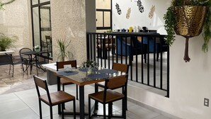 Un comedor moderno con una mesa de vidrio, sillas y una planta colgante.