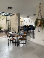 Un comedor moderno con una mesa de vidrio, sillas y una planta colgante.