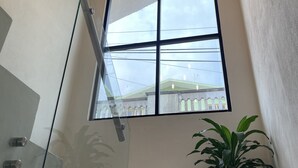 Un interior moderno con un ventanal grande, una lámpara de techo de madera y una planta en maceta.