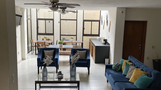 Un salón amplio con un sofá azul, una mesa de centro y un ventilador de techo.