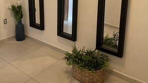 Tres espejos con marco negro en una pared, una planta en maceta y una cesta tejida con follaje.