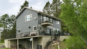 Une maison à deux étages dotée d’un balcon, d’un porche et de fondations en pierre.