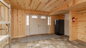 Un intérieur en bois avec une porte, un réfrigérateur noir et un extincteur.