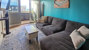 En moderne stue med en mørkegrå sofa, et sofabord og et billede på væggen.