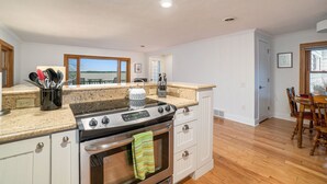 A kitchen with white cabinets, a granite countertop, and a stainless steel stove. - South Shore Bear Lake Family Cottage (Bear Lake)