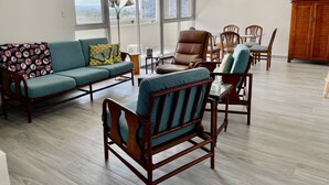 A spacious living room with a sofa, chairs, a dining table, and a cabinet. - OT7-3 bedrooms near to everything (Carolina)