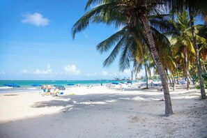 Une plage avec des palmiers, des parasols et des gens.