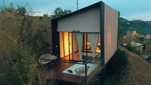 Una casa moderna de dos pisos con balcón, rodeada de vegetación natural.