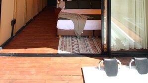 Un dormitorio moderno con un amplio ventanal corredero, una cama y una pequeña mesa con sillas.