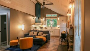A modern living room with a sofa, ottoman, and a dining area with a table and chairs. - Updated cottage "Beriozka" on Cedar Lake (Chester)