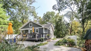 A two-story house with a porch, surrounded by trees and a gravel driveway. - Updated cottage "Beriozka" on Cedar Lake (Chester)