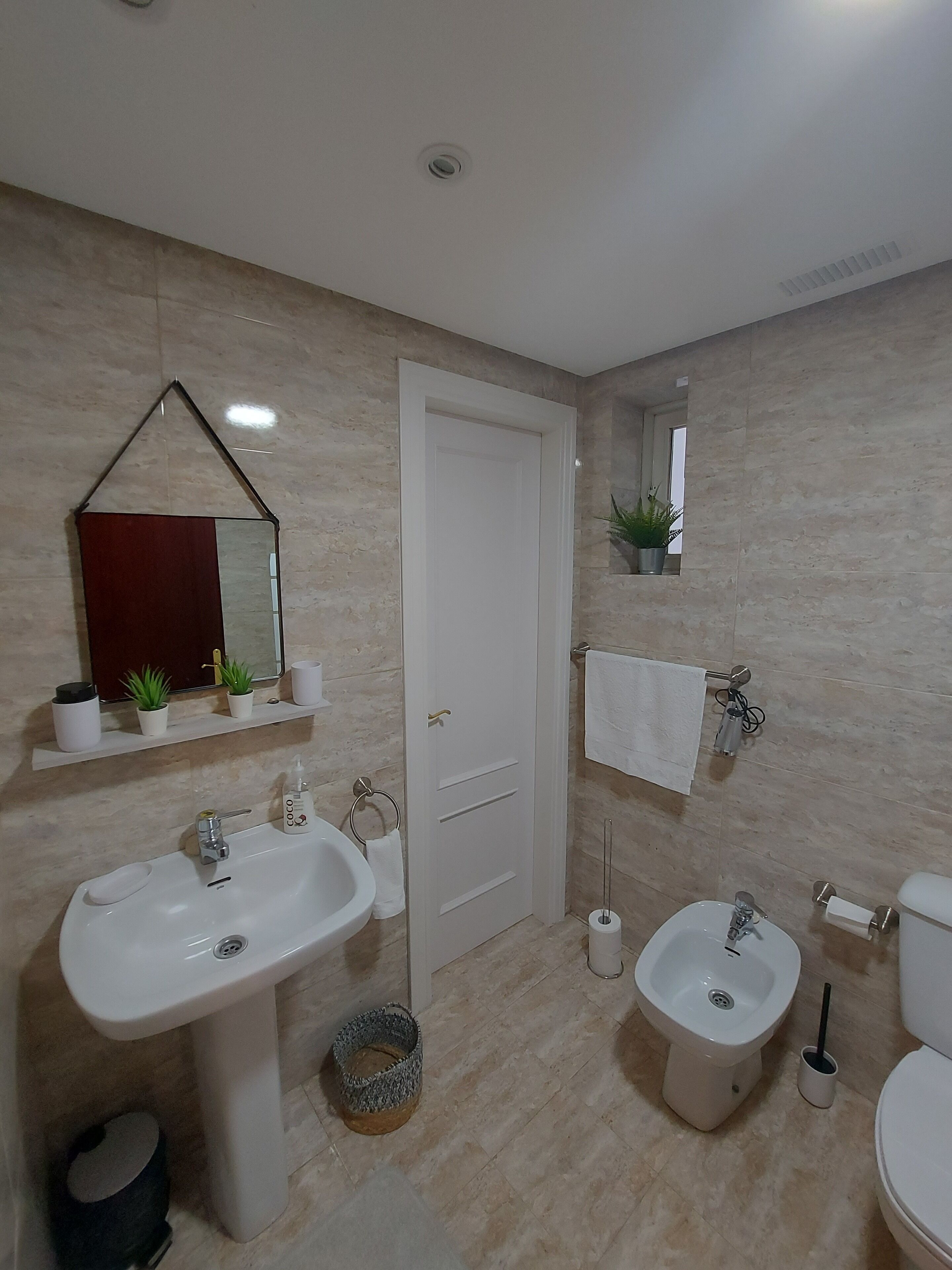 Une salle de bain comprenant un grand lavabo, un bidet, des toilettes, un miroir et un porte-serviettes.