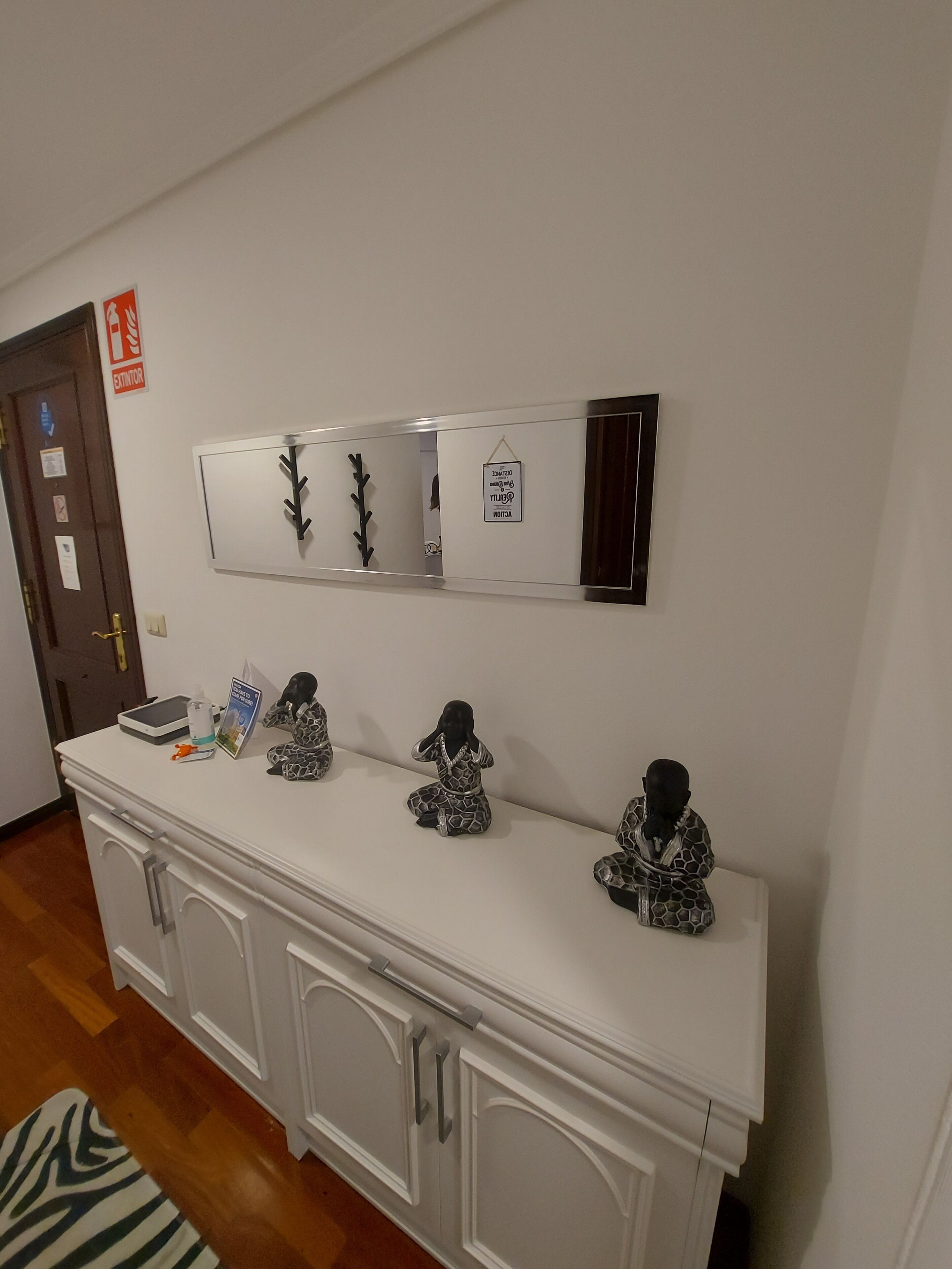 A white console table with decorative figurines, a mirror, and a sign indicating an exit.