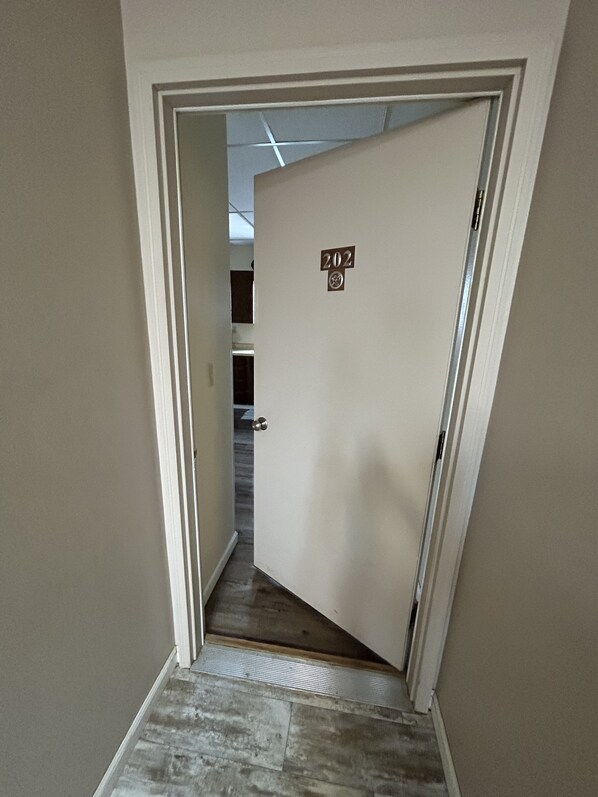 Un pasillo con una puerta que indica el número 202 y suelo de baldosas.
