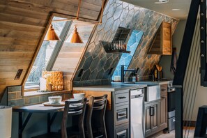 A modern kitchen with a stone backsplash, wooden accents, and a built-in stove.