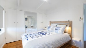Une chambre à coucher comprenant un lit, une tête de lit en bois, une table de chevet et une armoire.