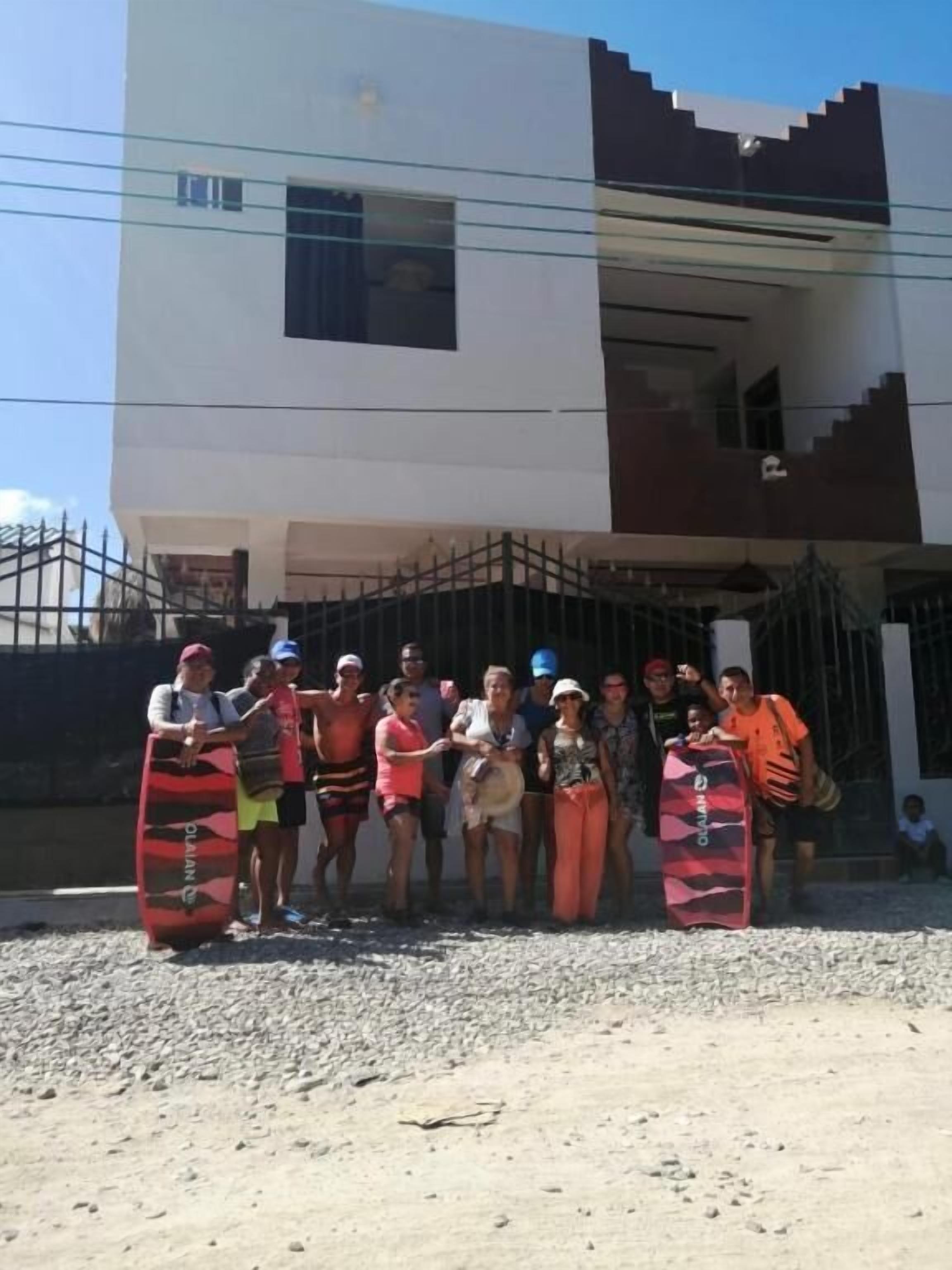 A group of people standing in front of a building with a modern architectural style, featuring a flat roof and a mix of white and dark panels.