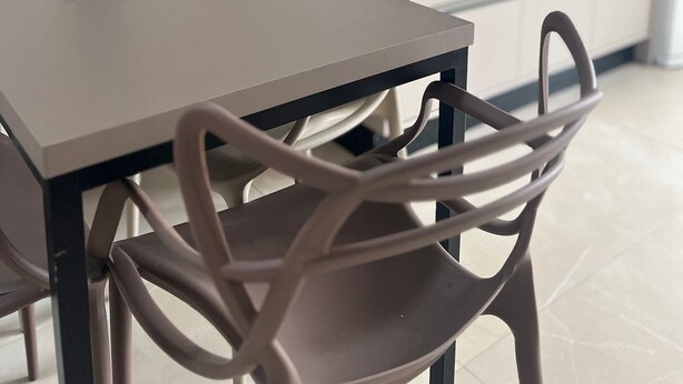 A modern kitchen with a dining table and chairs, a potted plant, and a built-in TV. - Residencial Bernardo (Bombinhas)