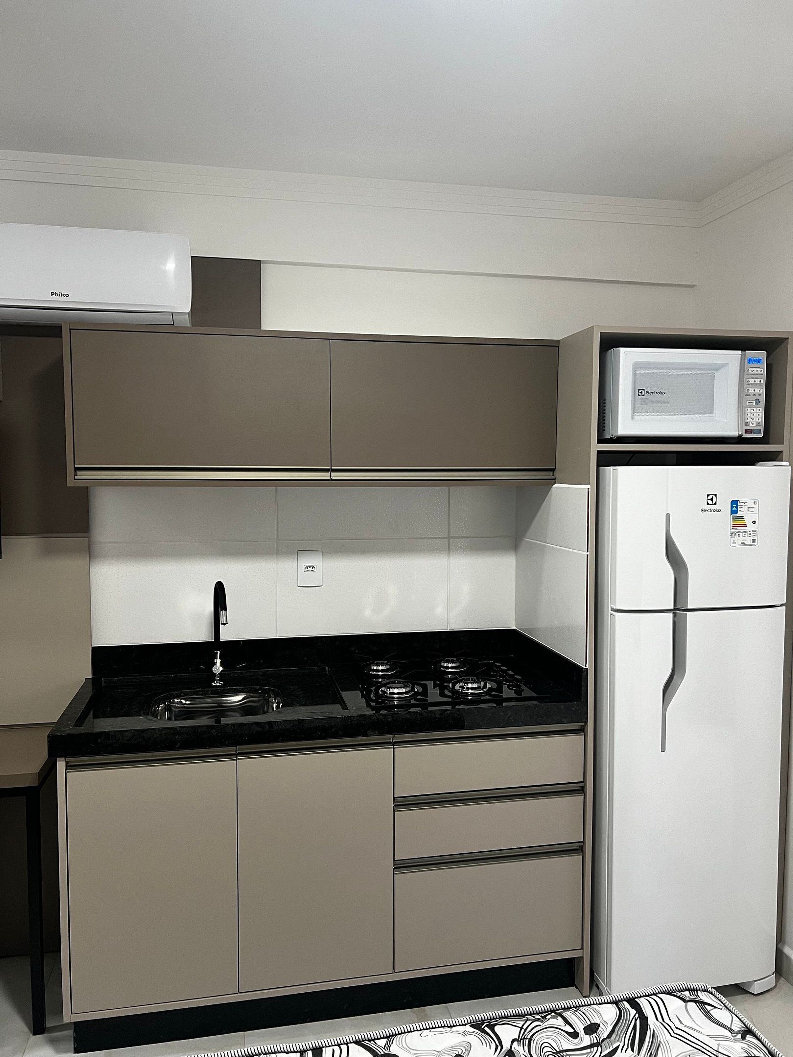 A compact kitchen with a gas stove, a microwave, and a refrigerator.