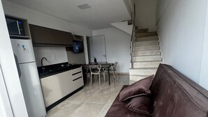 A modern apartment with a kitchen, dining area, and a sofa. - Residencial Bernardo (Bombinhas)