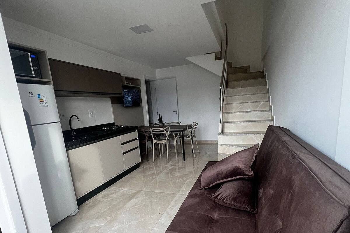 A modern apartment with a kitchen, dining area, and a sofa.