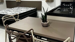 A compact kitchen with a dining area, a small potted plant, and a view through the window. - Residencial Bernardo (Bombinhas)