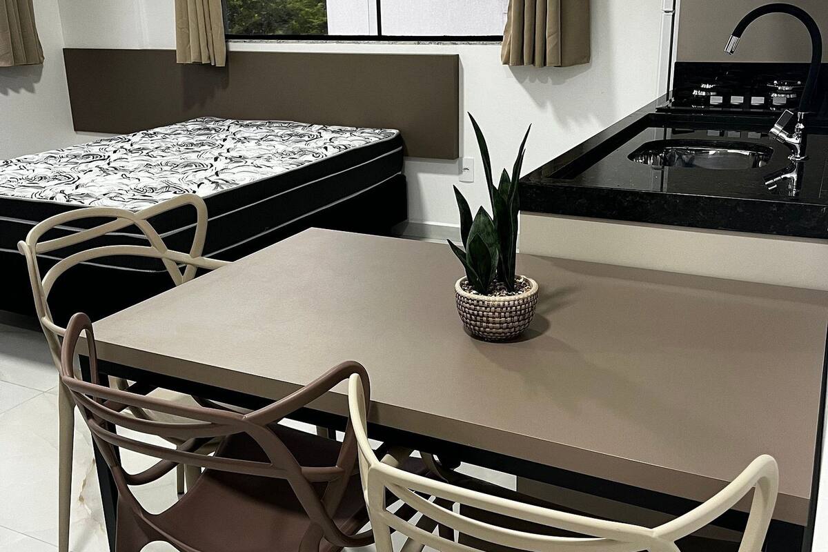 A compact kitchen with a dining area, a small potted plant, and a view through the window.