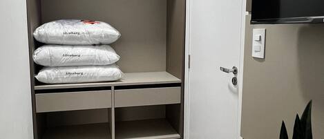 Una habitación compacta con armario empotrado que contiene tres maletas grandes, una mesa de comedor con una silla y una planta en maceta.