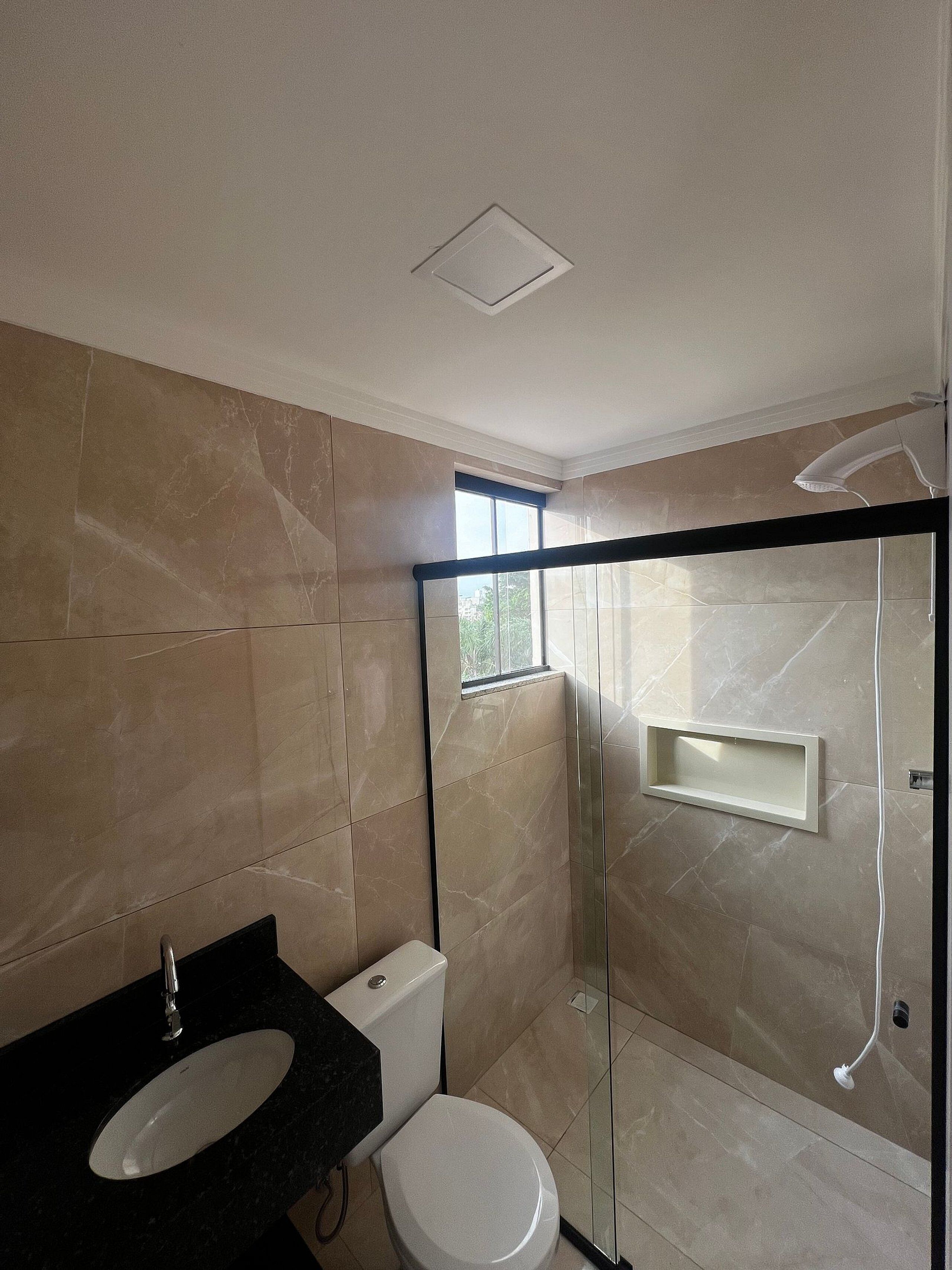 Une salle de bain moderne avec un lavabo noir, des toilettes blanches et une douche à parois de verre.