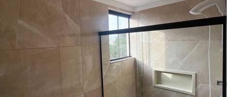 Une salle de bain moderne avec un lavabo noir, des toilettes blanches et une douche à parois de verre.