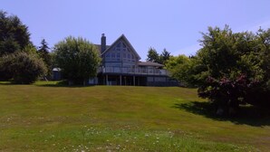 A large house with a prominent gabled roof and a covered porch area. - Azure Ocean Beach House (Port McNeill)