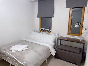 A neatly made bed with white linens, a bedside table with a lamp, and a window with a view. - Central 2-bed Apartment in Greater Manchester (Manchester)