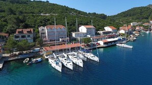 A coastal town with a marina, houses, and a hilly backdrop.