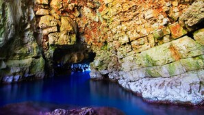 A cave with natural rock formations and a pool of water.