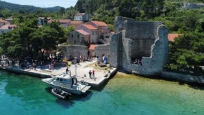 A coastal town with a historic stone wall, a dock with boats, and buildings with red roofs.