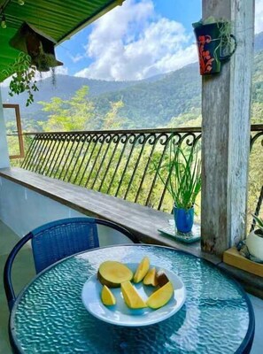 A balcony with a glass table, a chair, and a plate of sliced fruit.