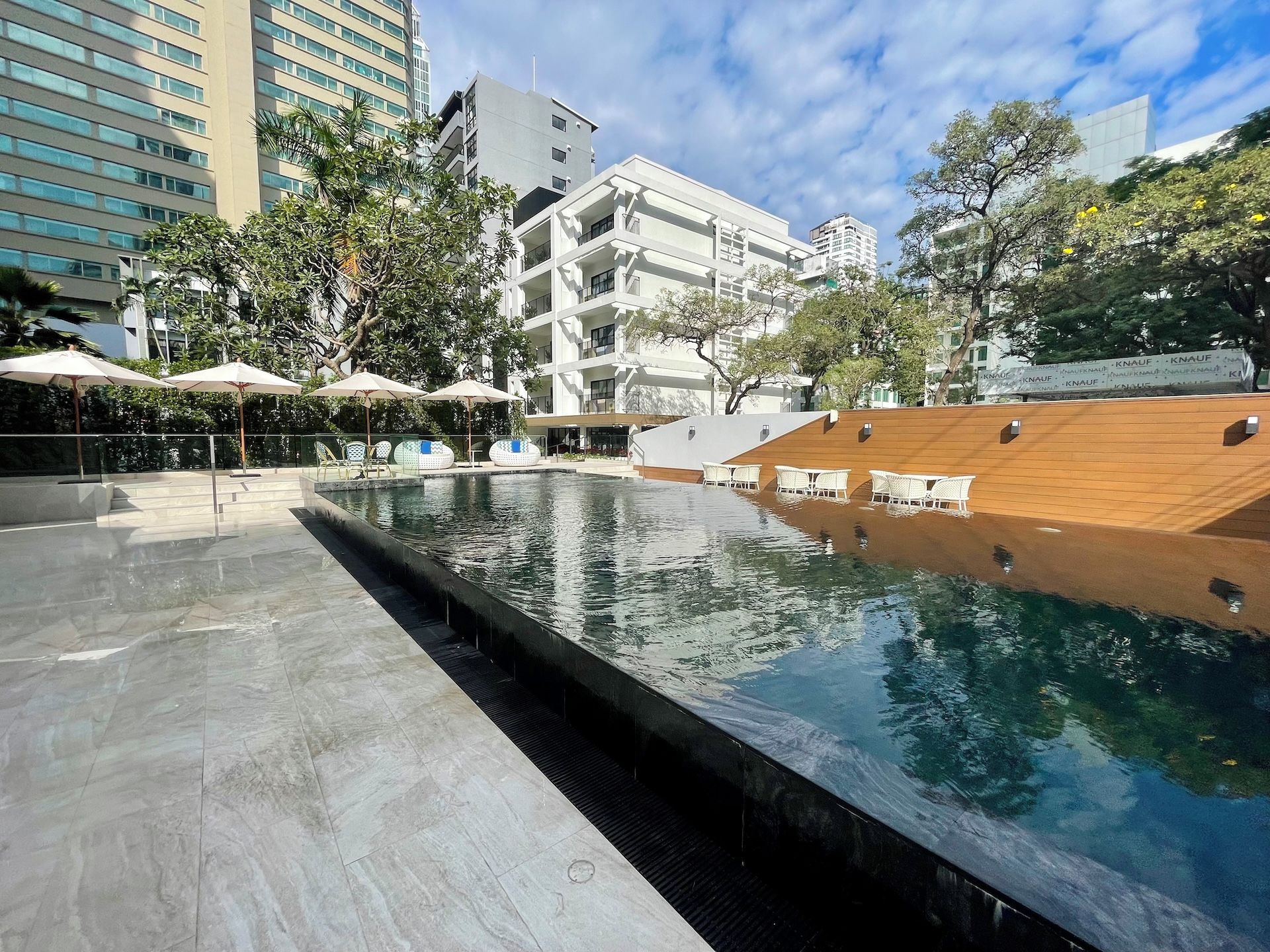 A modern pool area with a clear pool, lounge chairs, and umbrellas.