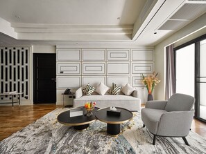 A modern living room with a sofa, two round coffee tables, a patterned armchair, and a decorative vase. - Floral Court Hotel and Residence (Bangkok)