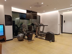 A gym with cardio machines, a stationary bike, and a large exercise ball. - Floral Court Hotel and Residence (Bangkok)
